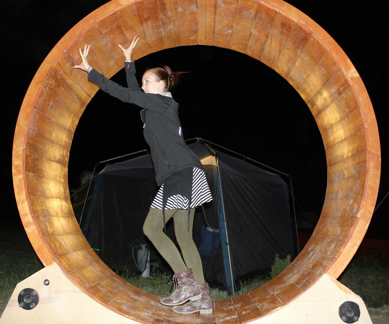 A woman standing inside of a human sized hamster wheel